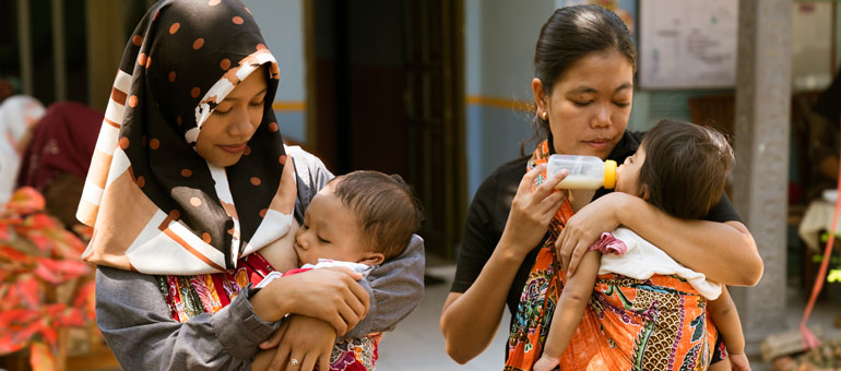 Two ladies feeding babies in Indonesia