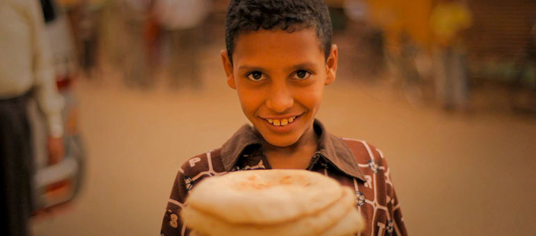 Egyptian boy holding baladi bread in the street