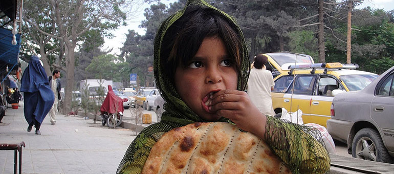 Girl eating bread in the street, Afghanistan