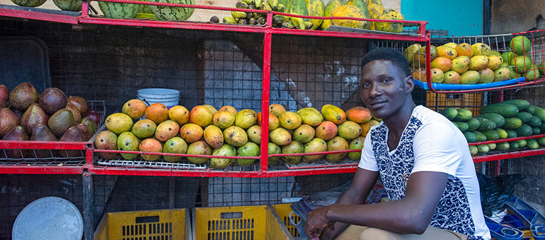 Man sitting in front of boxes of fruits in Tanzania
