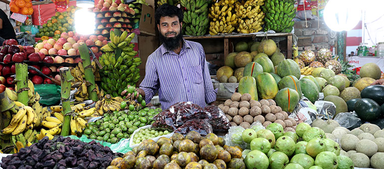 Man selling fruits and vegetables in a city market in Bangladesh