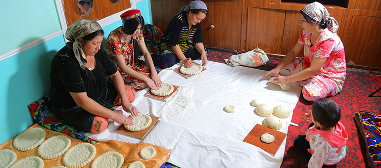 Women preparing bread while sitting down in a circle