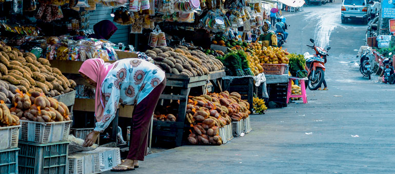 a lady arranging food in open air stalls in Indonesia