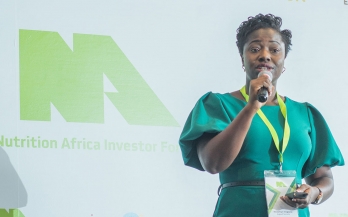 African woman in bright green dress presenting at the Nutrition Africa Investor Forum (NAIF)