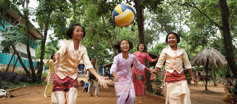 Four young girls playing ball and smiling