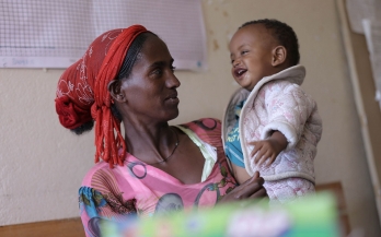 Ethiopian woman holds her baby and smiles at his laugh