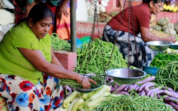 Two women weighting vegetables in the market