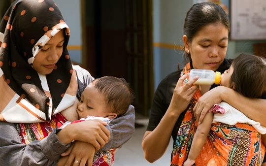 Two ladies feeding their babies in Indonesia