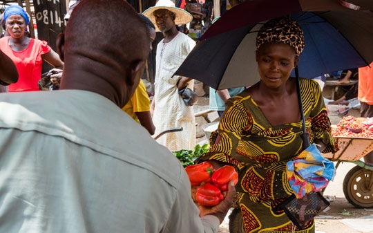 Woman buying food from a street vendor in Africa while holding the umbrella
