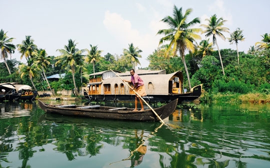 Man in Kerala, India, pushing his boat on the river